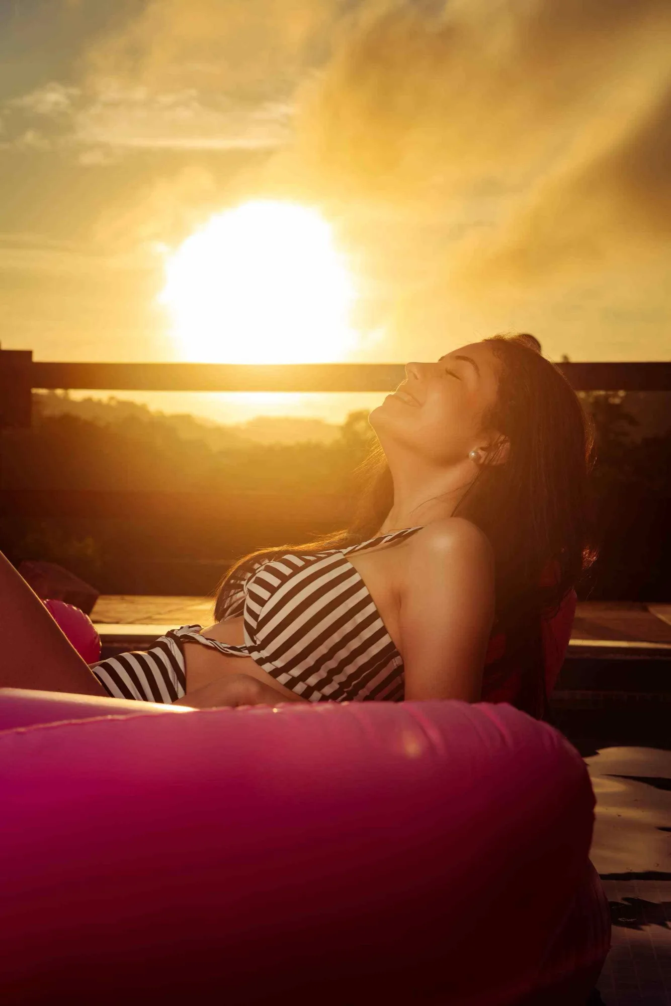 A woman relaxing by the pool in the golden light of sunset
