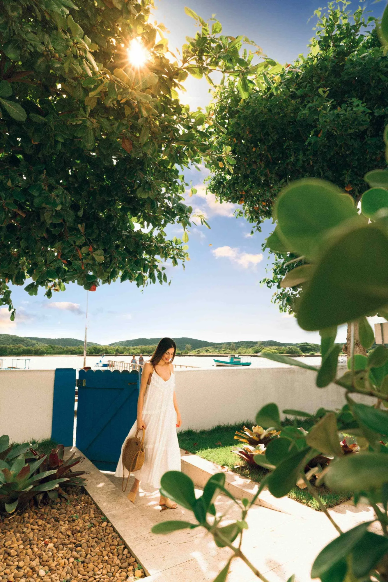 A traveler in a white dress in a waterfront garden